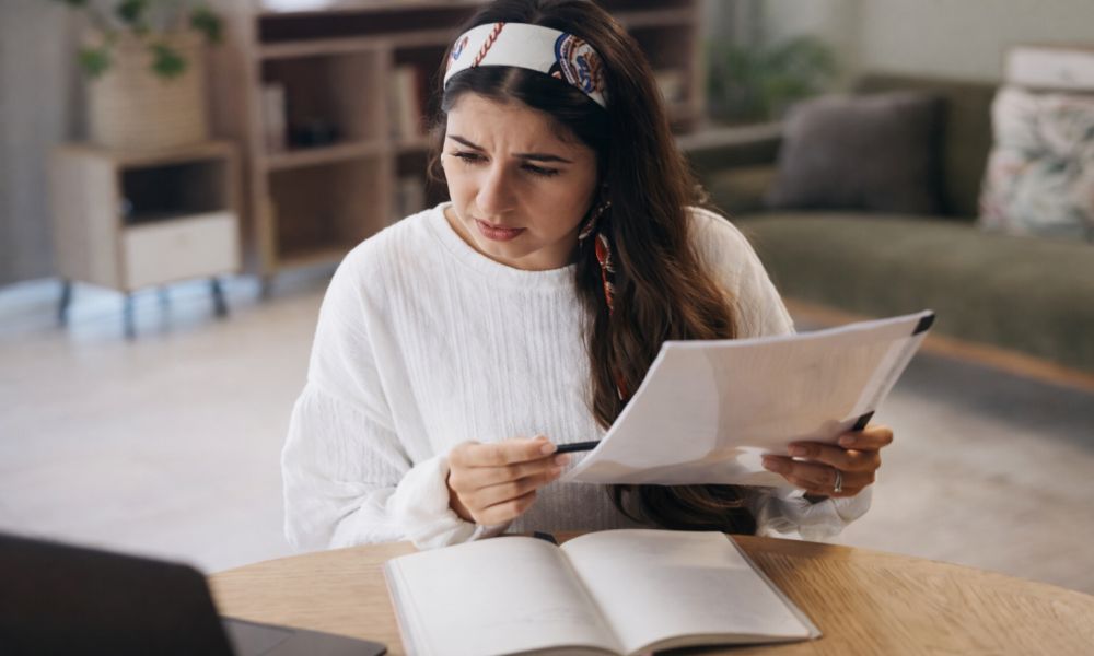 Žena pažljivo pregledava dokumenta i račune, pripremajući poresku prijavu za prihod od izdavanja nekretnine