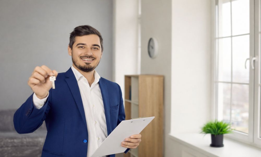Muškarac drži ključ stana i dokumente, simbolizujući izdavanje nekretnine i poreske obaveze između vlasnika i zakupca